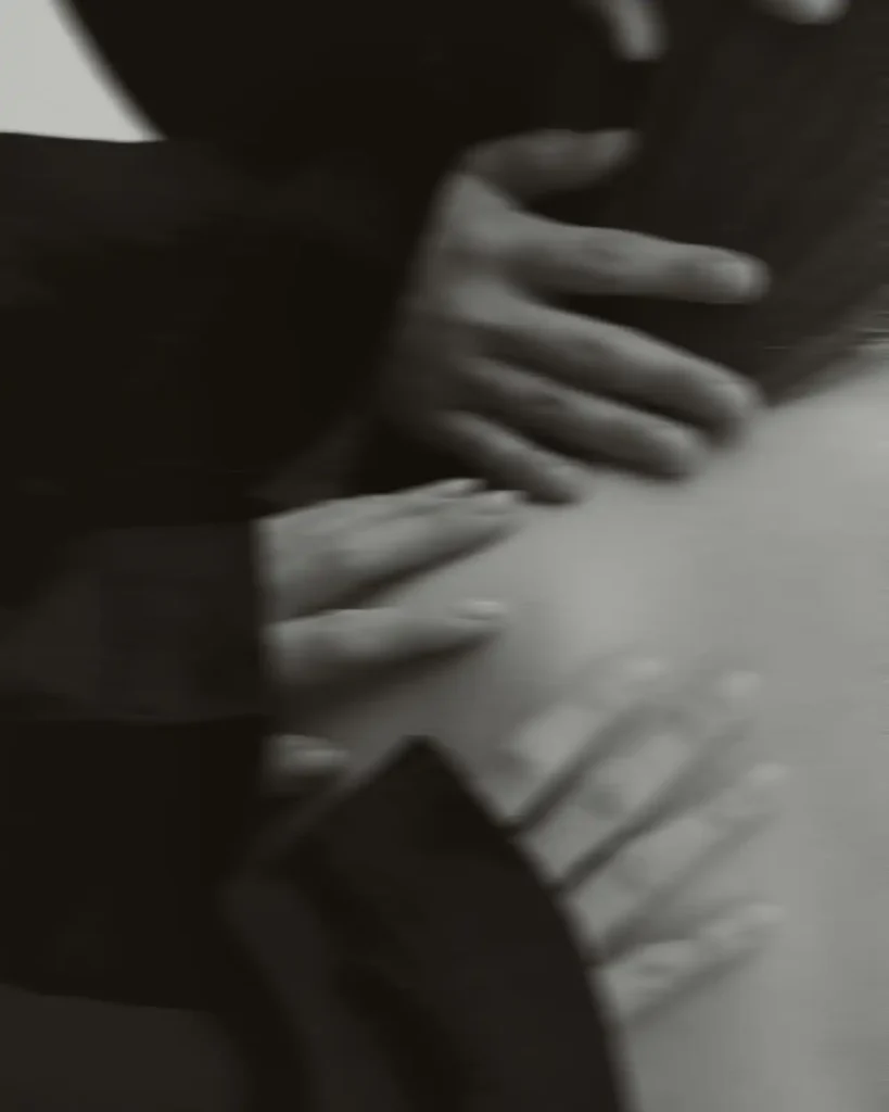 Hands resting in shadow, evoking care, grounding and restoration